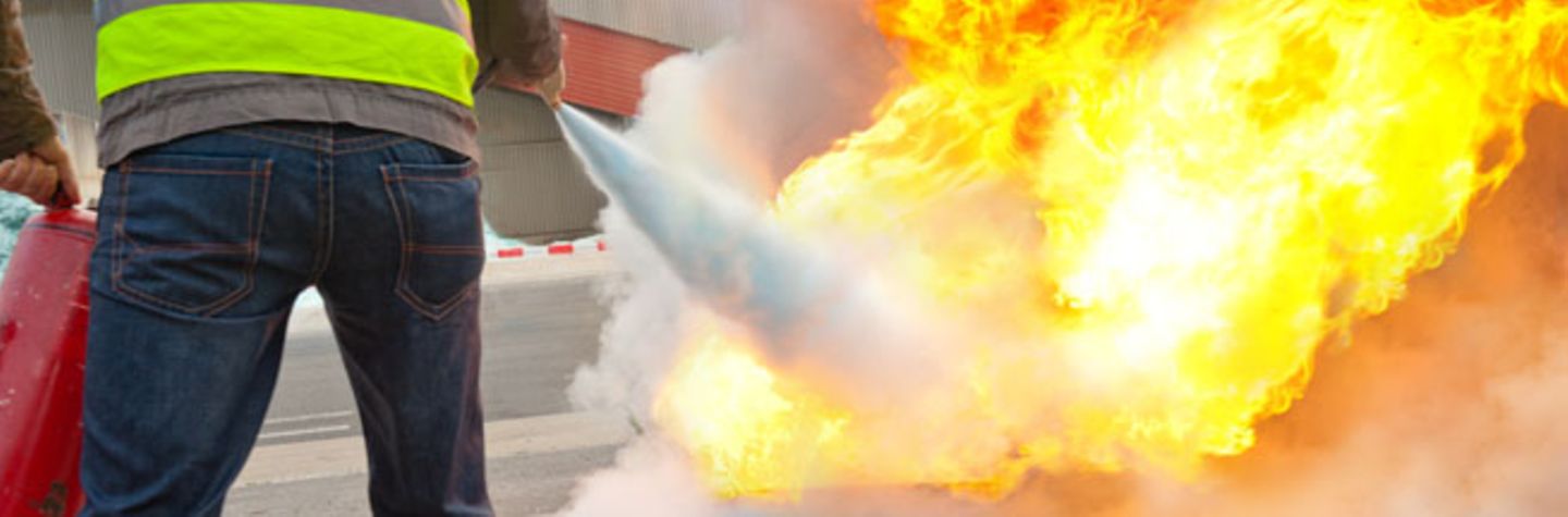 Brandschutz Ein Brandschutzhelfer löscht mit einem Feuerlöscher einen Brand